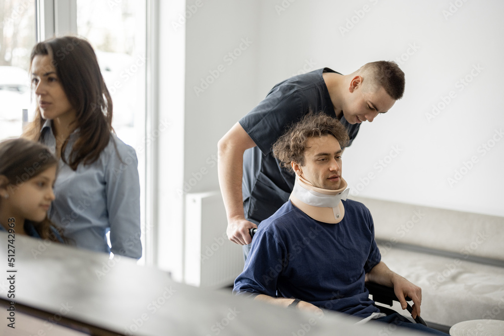 Young people in the lobby of the clinic. Rehabilitologist taking care of patient in wheelchair, woma