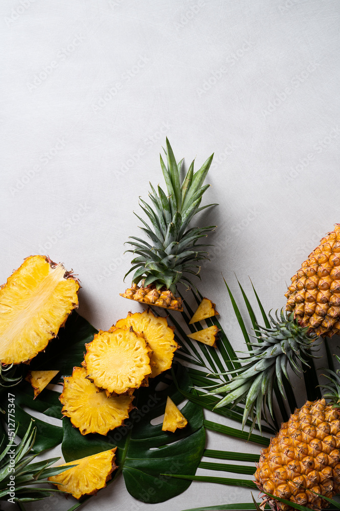 Fresh cut pineapple with tropical leaves on dark blue background.