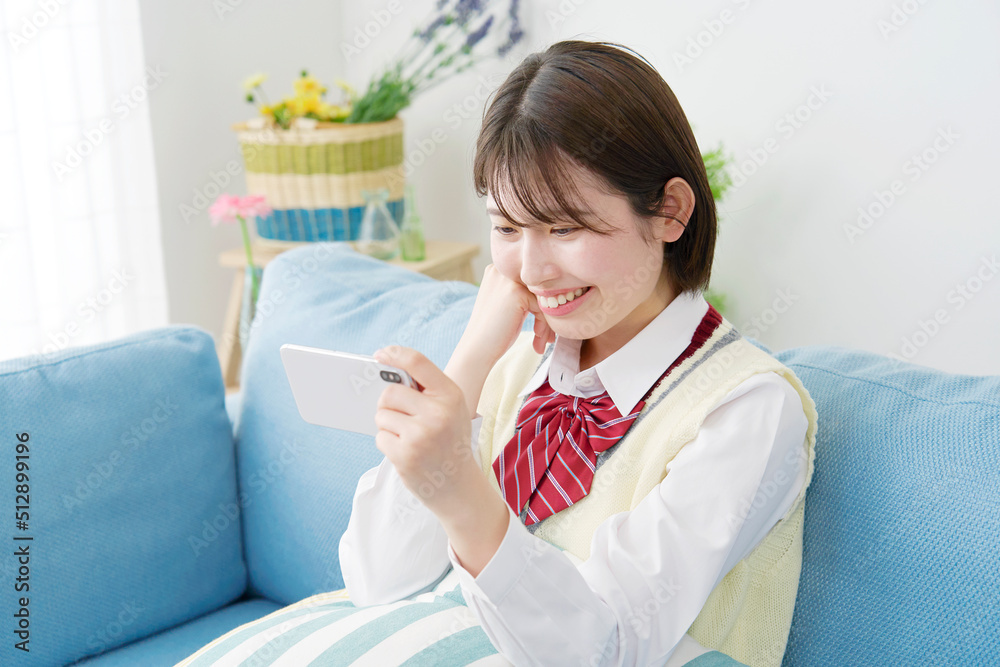 リビングでスマホを見る女子高生