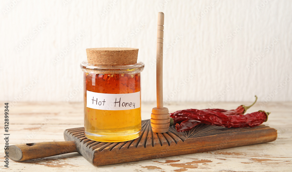 Jar of hot honey and dry chili peppers on wooden table