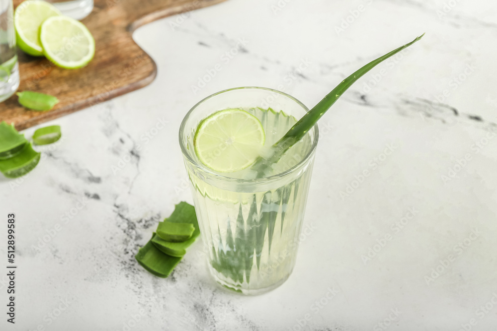 Glass of aloe juice and leaves on white background