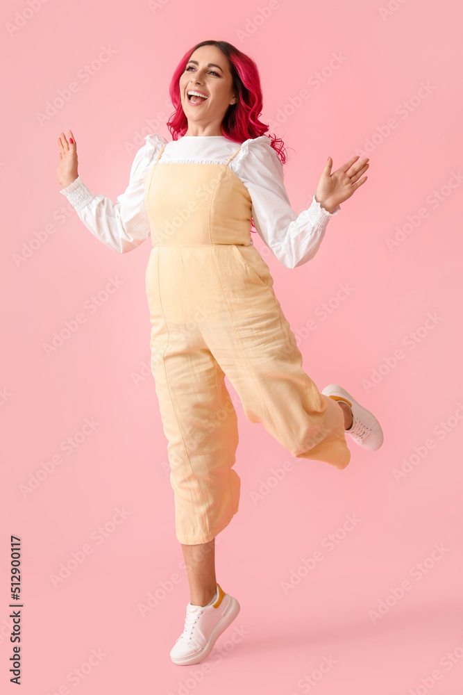 Beautiful woman with bright hair jumping on pink background