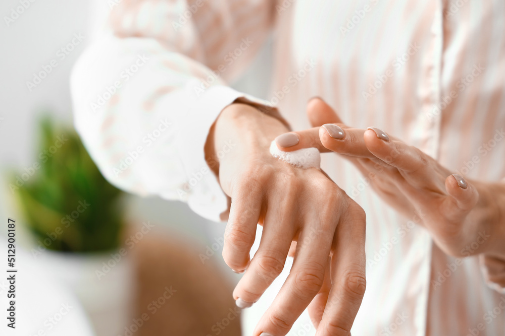 Morning of mature woman applying hand cream at home, closeup