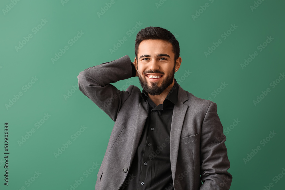 Fashionable bearded man keeping hand behind head on green background