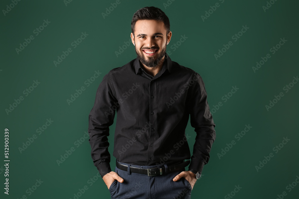 Bearded man keeping hands in pockets on green background