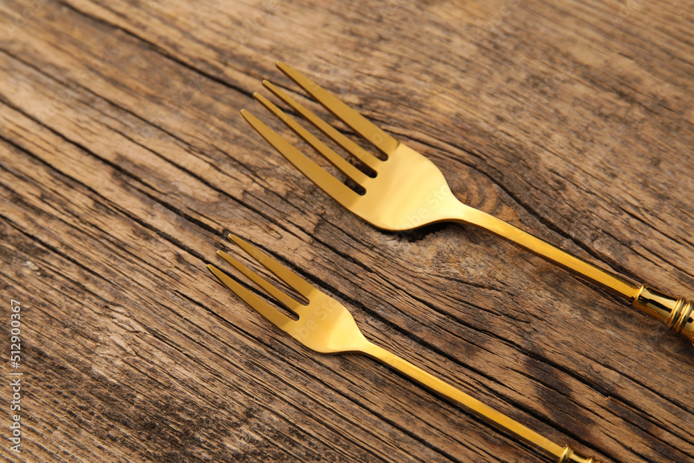 Stylish stainless steel forks on wooden background, closeup