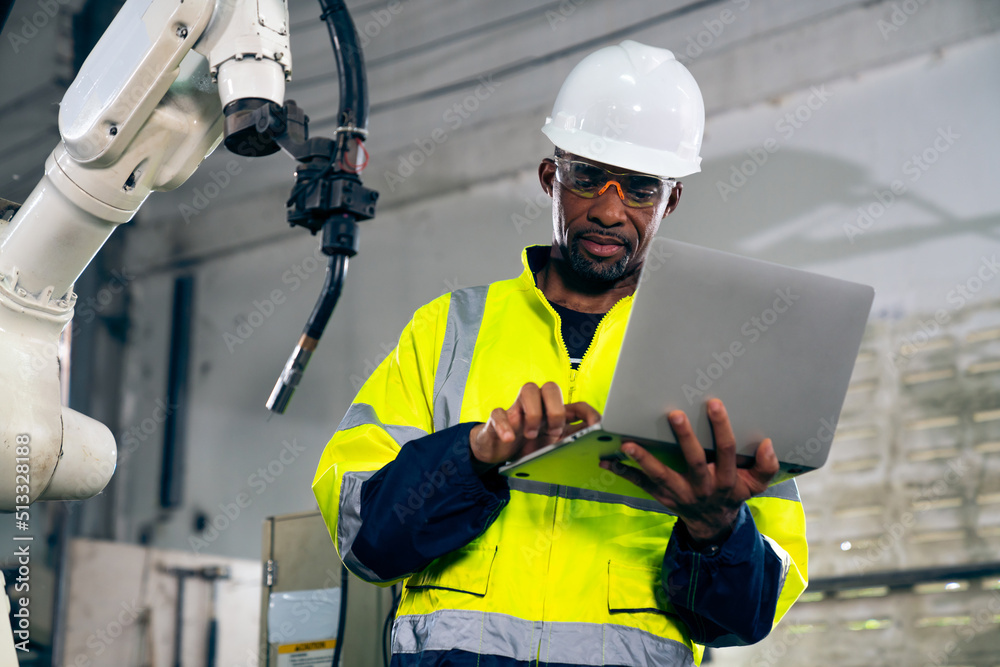 African American factory worker working with adept robotic arm in a workshop . Industry robot progra