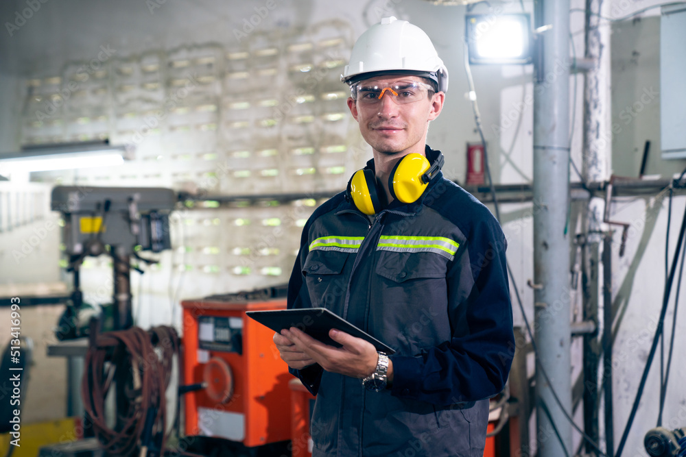 Young factory worker using adept tablet computer in a workshop building . Industrial technology and 