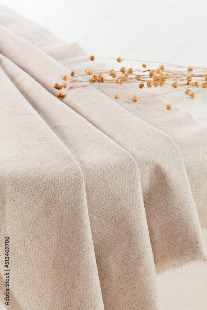 folded linen cloth with a bouquet of dry flax on table.