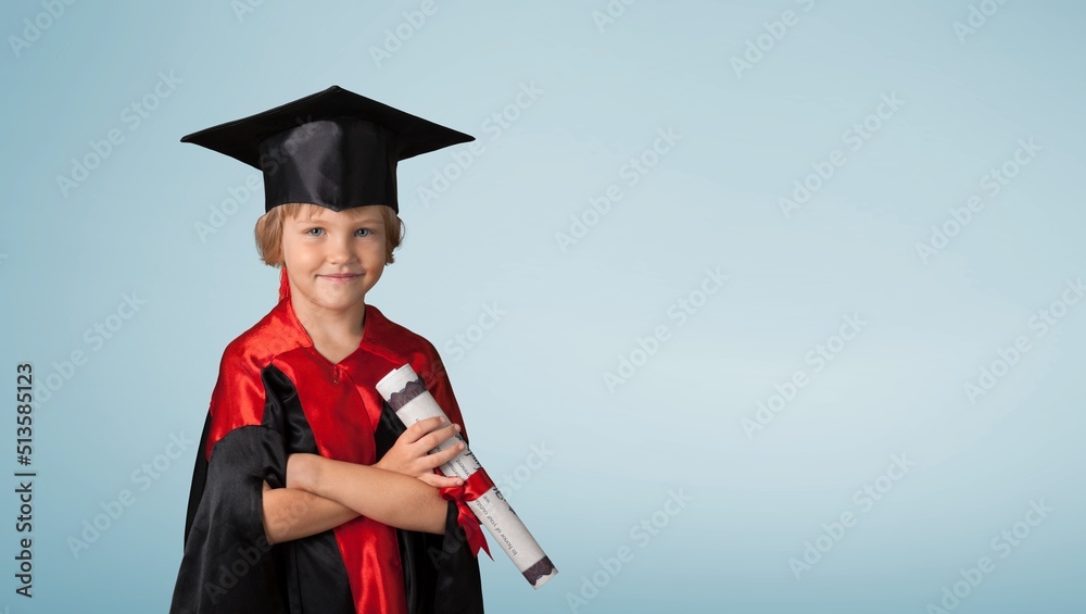 Cute kid wearing graduation cap and ceremony robe with certificate diploma. Graduate celebrating gra