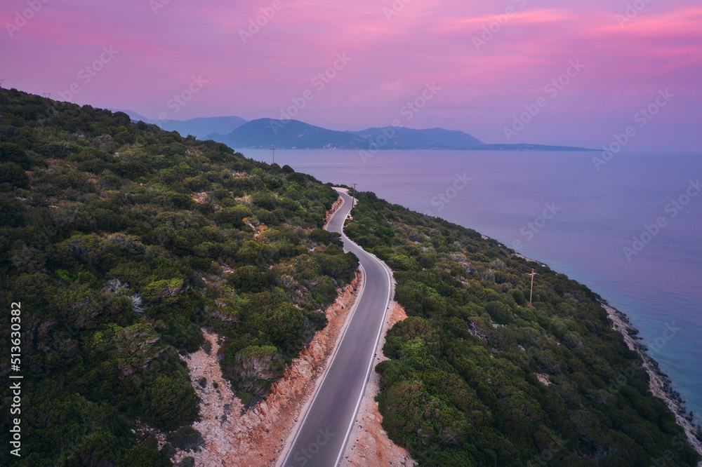 蓝色大海附近的道路鸟瞰图，夏天日落时的森林。在希腊莱夫卡达旅行。俯视图o