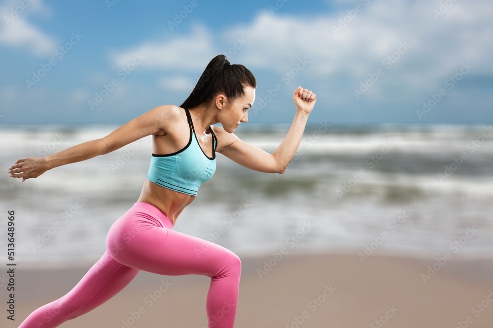 A female doing sport to keep fit. Mature woman running along the shore of the beach.