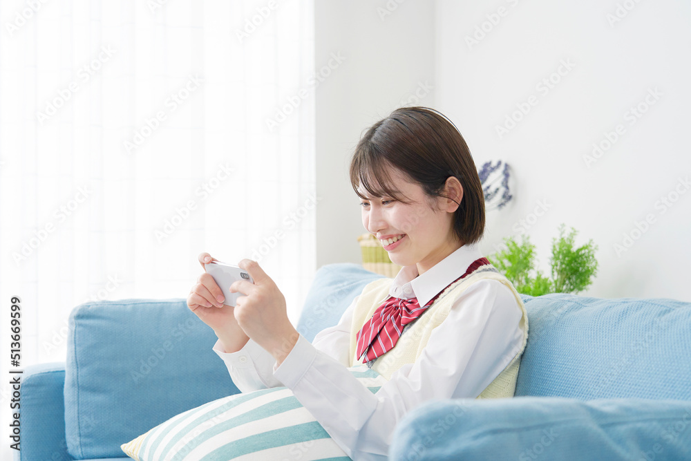 リビングでスマホを見る女子高生