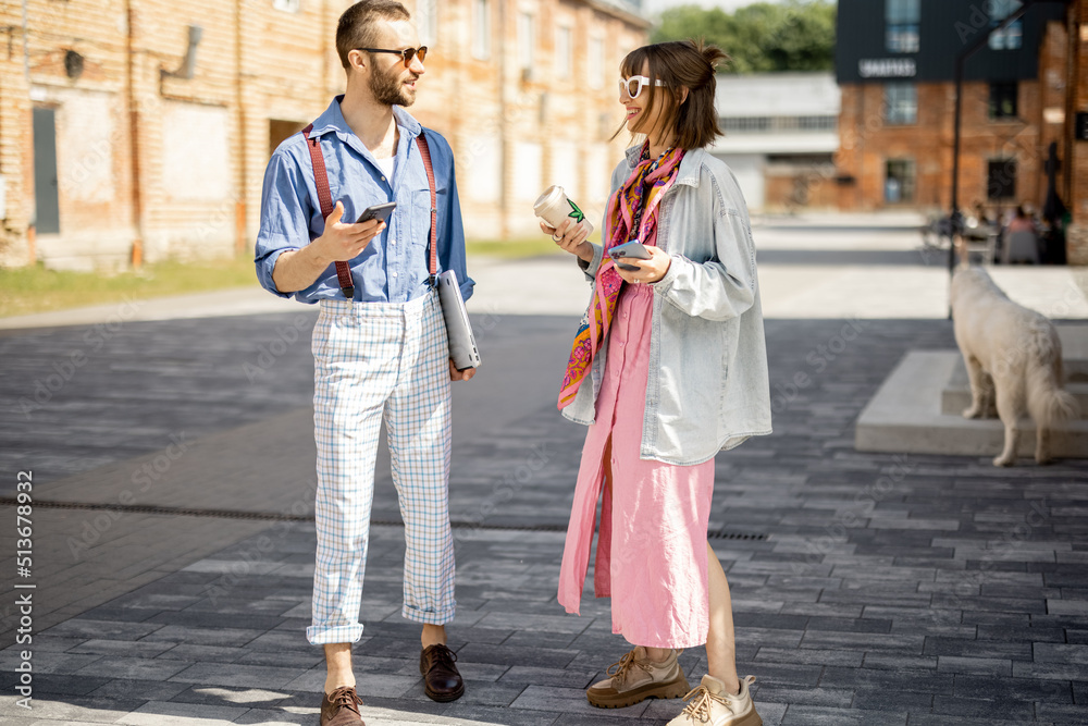 Young stylish couple have some conversation while walking together during a coffee break. Young hips