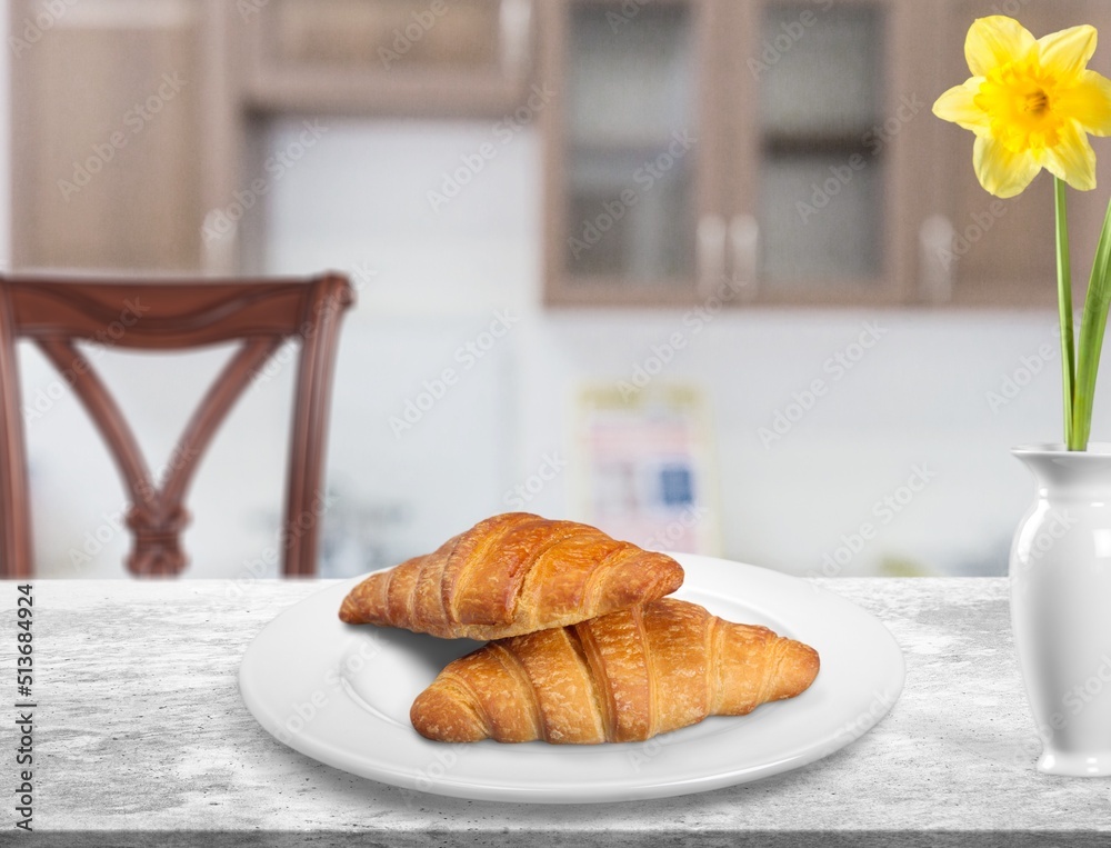 Croissants in white plate on the kitchen background