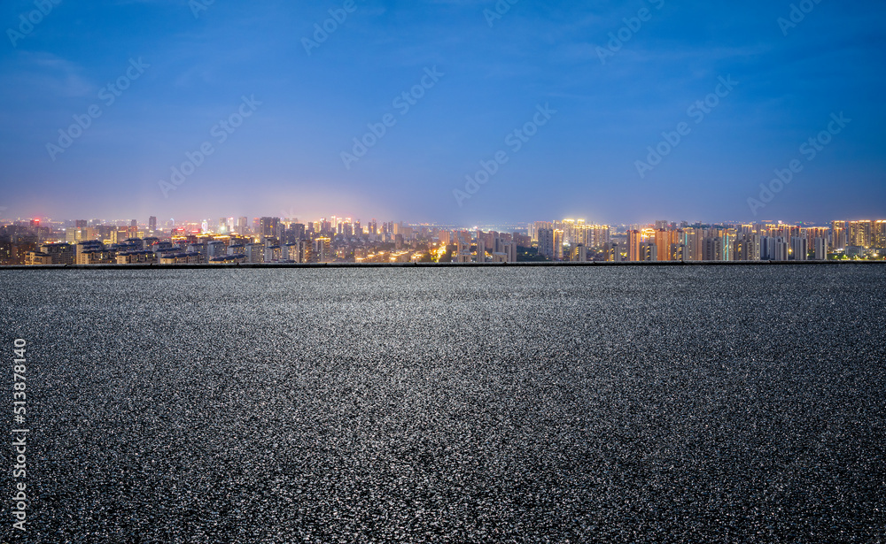 沥青路和现代城市天际线，夜晚有建筑景观。高角度视野。