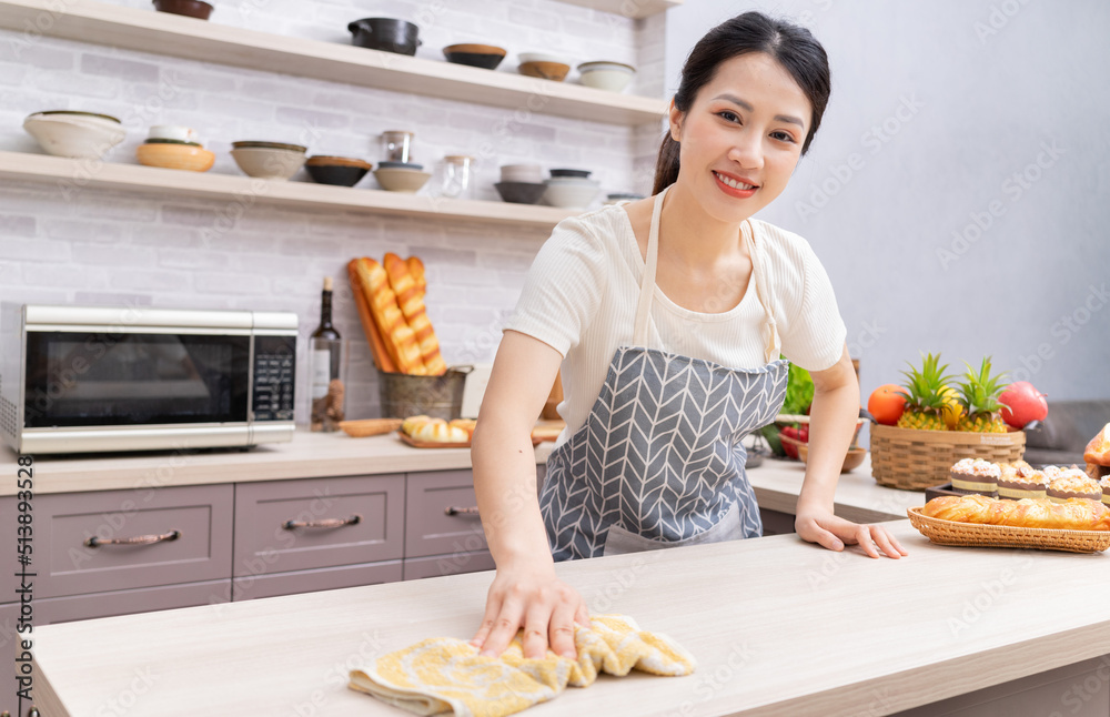 年轻的亚洲女人做饭后打扫厨房。