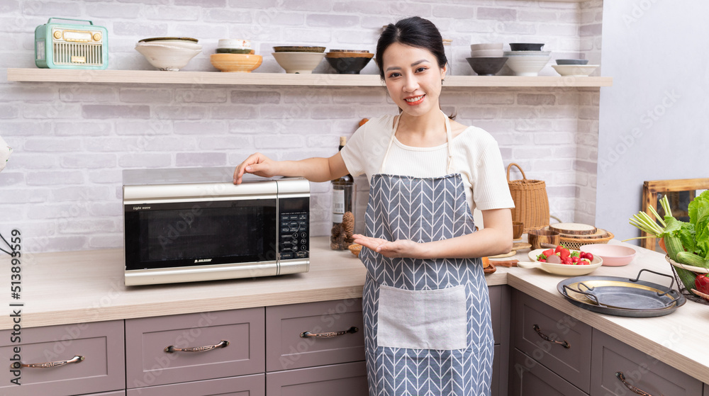 年轻的亚洲妇女正在厨房做饭。