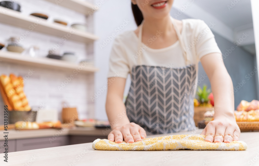 年轻的亚洲女人在做饭后打扫厨房。