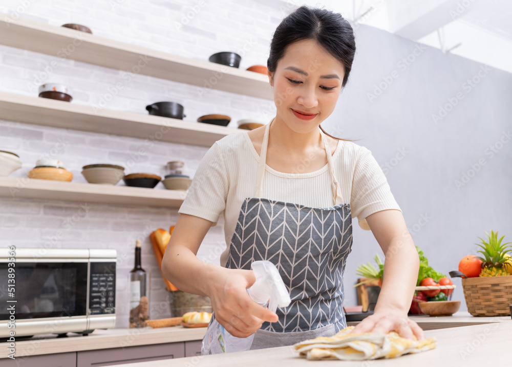 年轻的亚洲女人在做饭后打扫厨房。