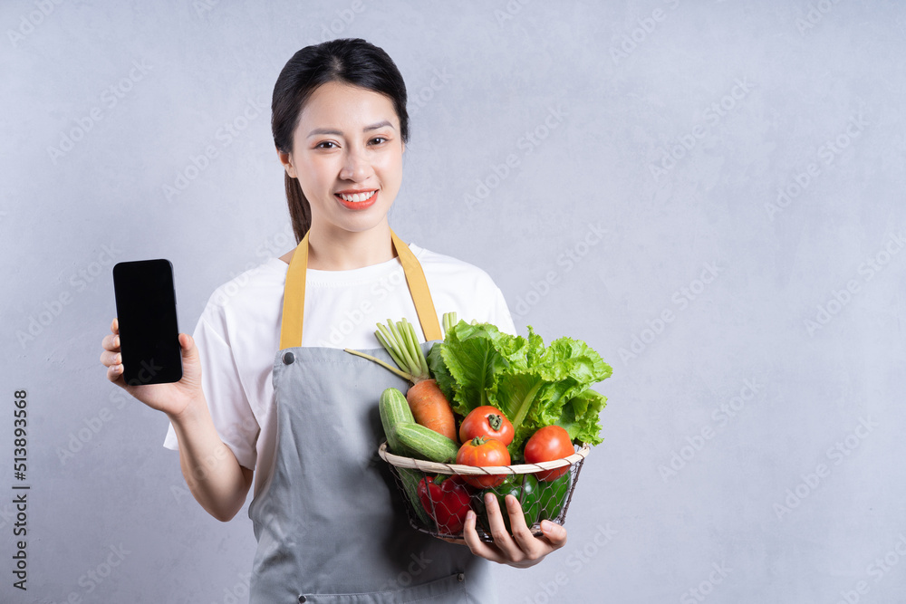 Young Asian woman holding vegetables on background