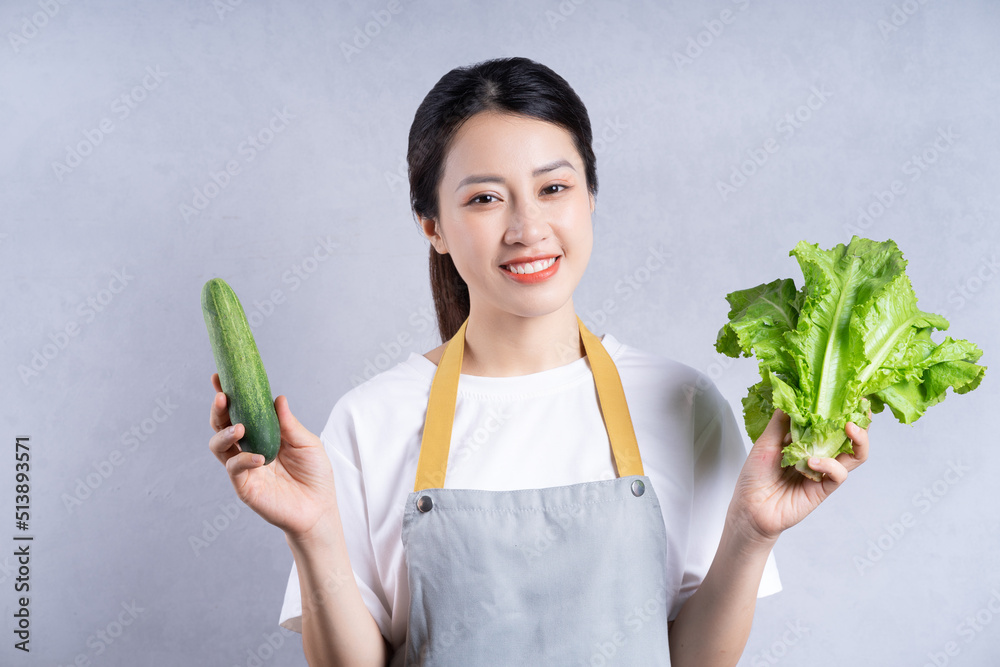 背景是拿着蔬菜的年轻亚洲女人