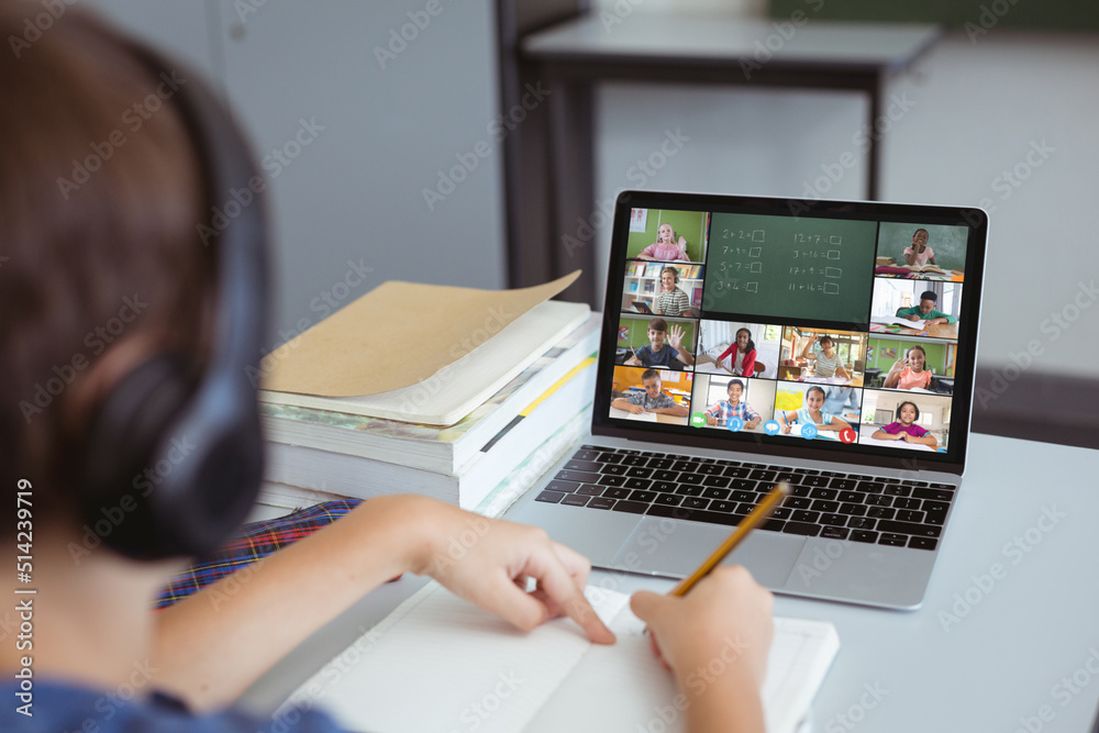 Caucasian boy writing maths problems while studying online over video call on laptop at home