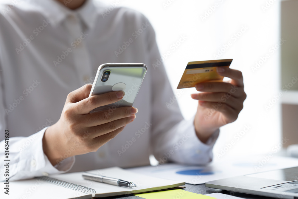 Online payment, woman hands holding a credit card and using smart phone for online shopping, young w