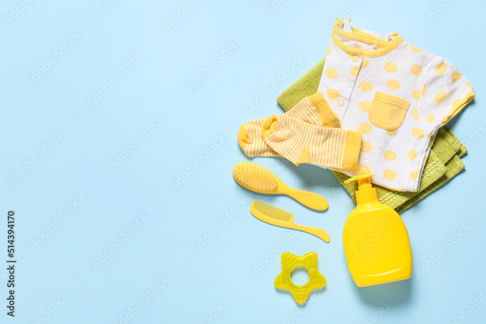 Cute baby clothes and different bath accessories on blue background