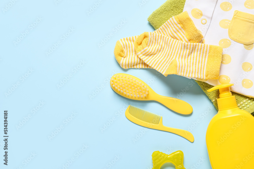 Baby clothes and different bath accessories on blue background, closeup