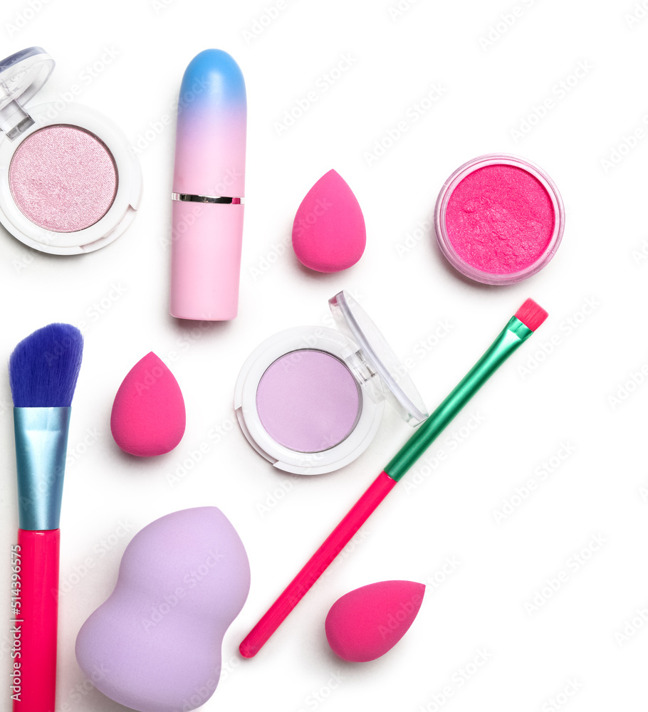 Different cosmetics, makeup brushes and sponges on white background