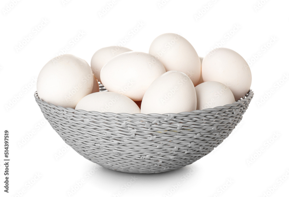 Wicker basket with chicken eggs on white background