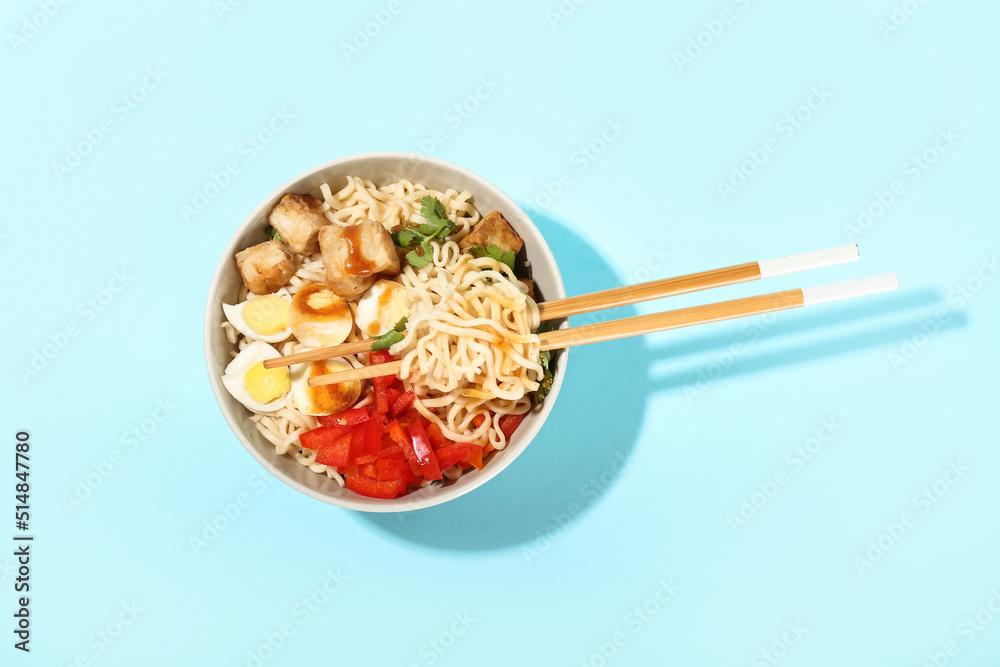 Bowl of tasty noodles with chicken on blue background