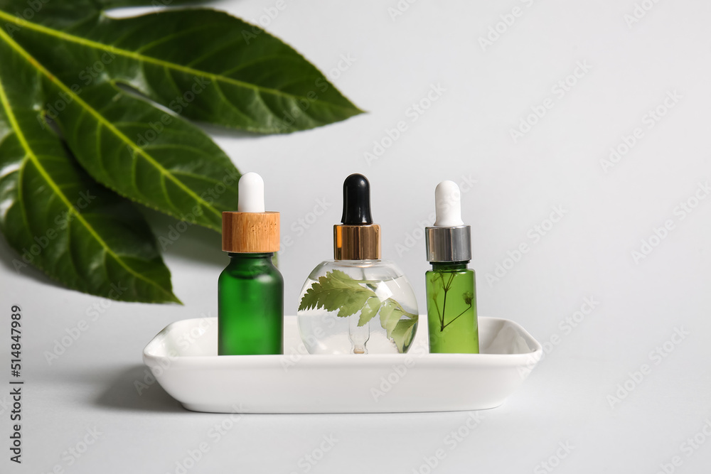 Bowl with bottles of natural serum on white background