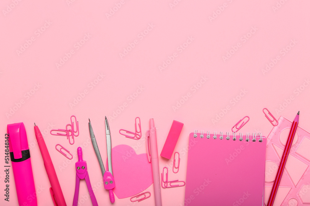 Pink paper clips with stationery supplies on color background