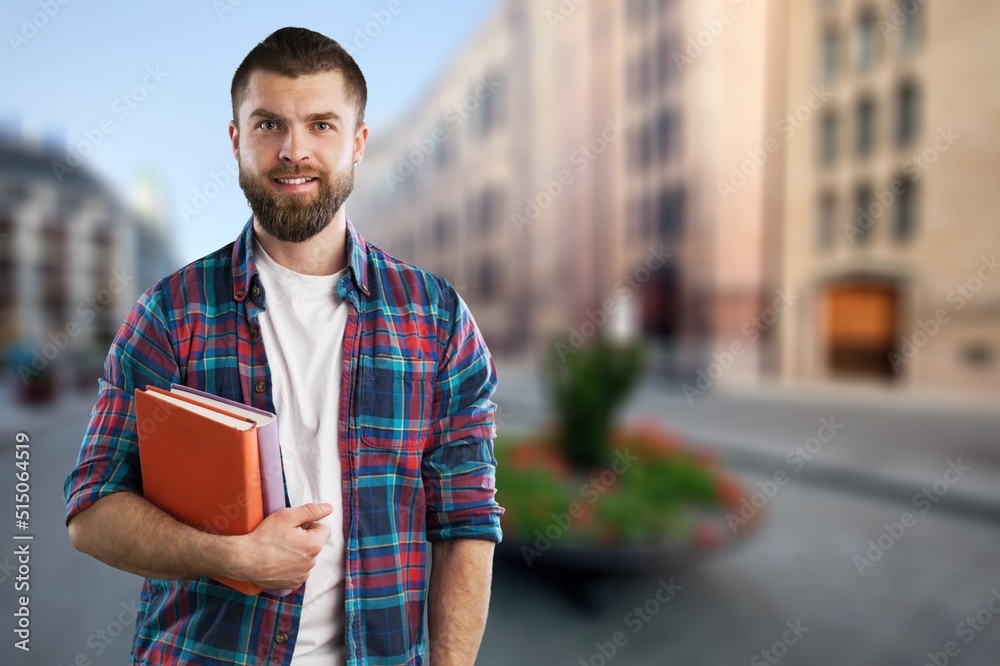 Authentic young handsome man standing on the street. Smiling student in university campus. Education