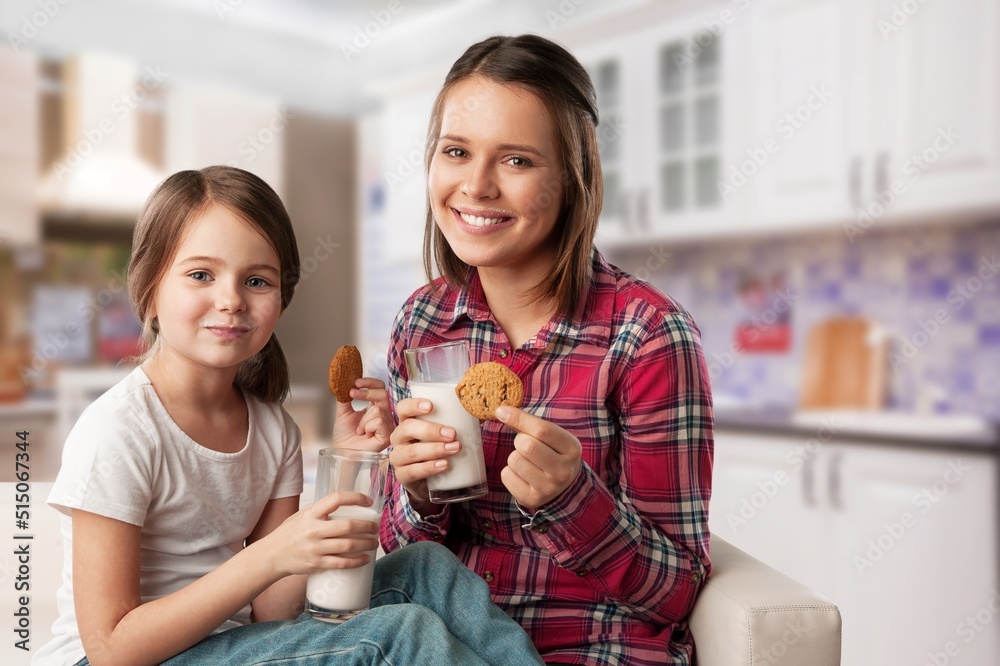 Happy Family Mother And Daughter Holding Glasses While Sitting Together In Kitchen, Enjoying Healthy