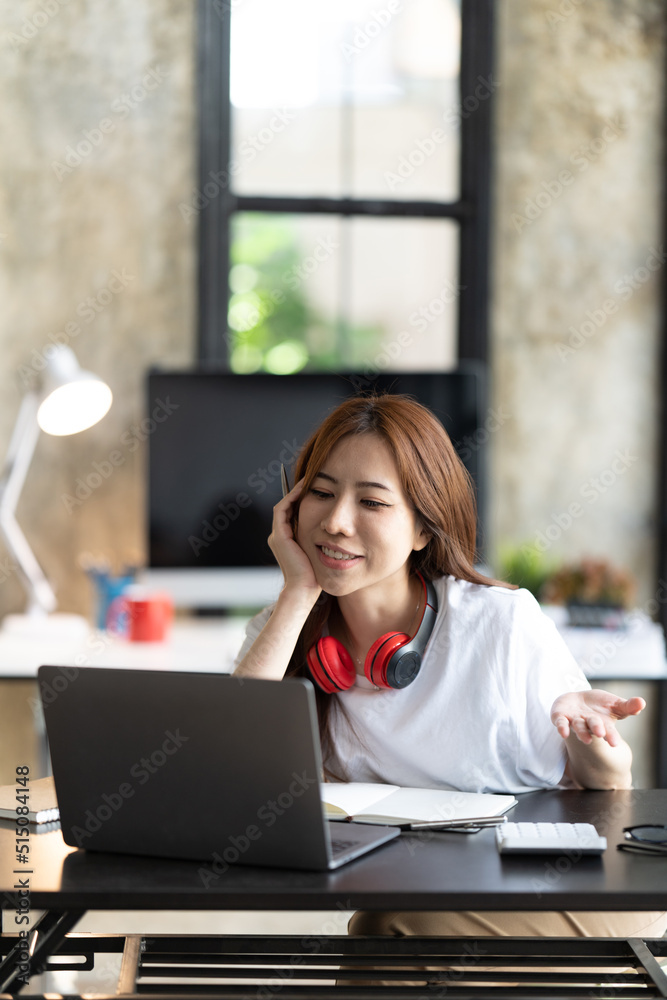 一名年轻的女学生坐在桌子旁，学习时使用电脑笔记本电脑。