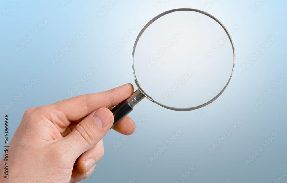 Hand holding magnifying glass on the background. Information search, data analysis and verification 