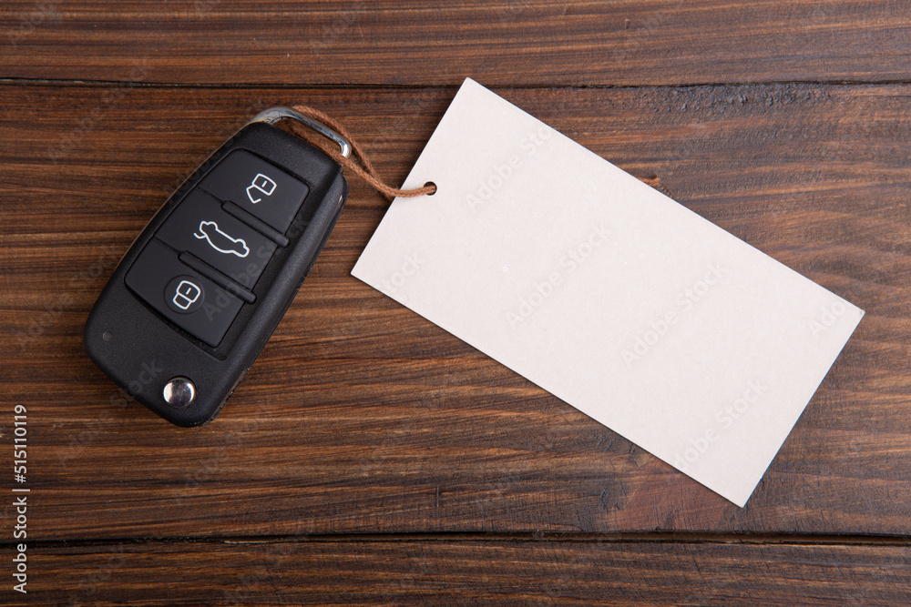 Car insurance or rent concept. Vehicle security key with blank tag on the wooden background