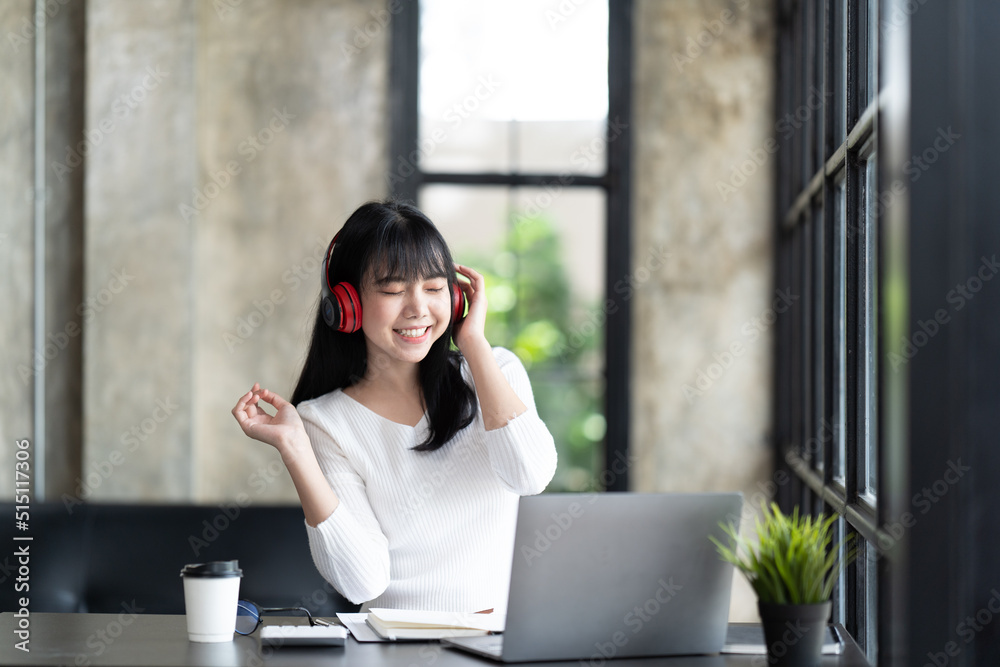 一名年轻的女学生坐在桌子旁，学习时使用电脑笔记本电脑。