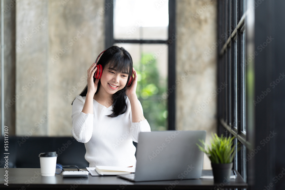 一名年轻的女学生坐在桌子旁，学习时使用电脑笔记本电脑。