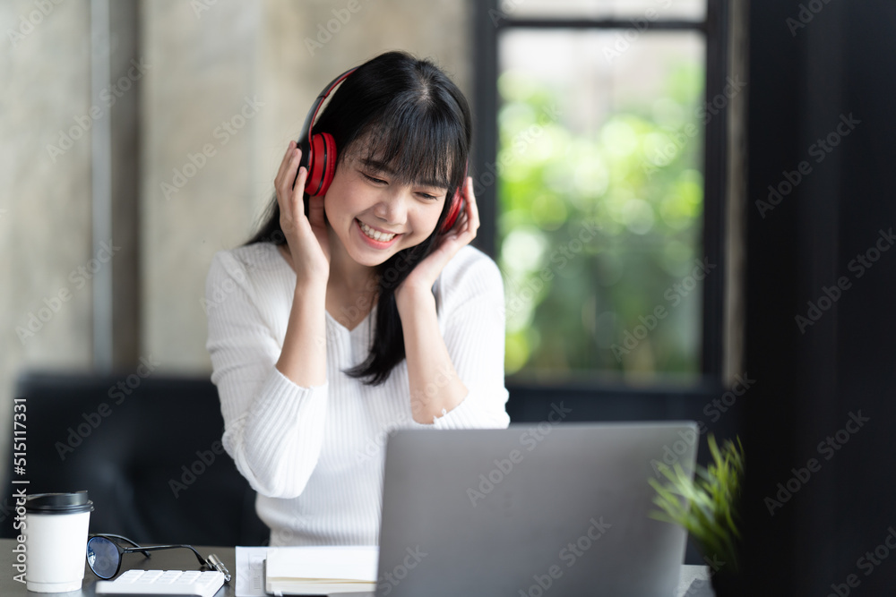 一名年轻的女学生坐在桌子旁，学习时使用电脑笔记本电脑。