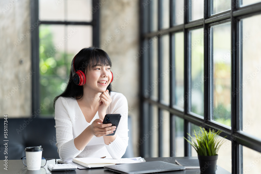 一名年轻的女学生坐在桌子旁，学习时使用电脑笔记本电脑。