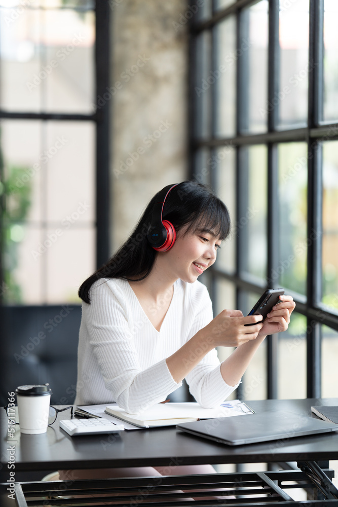 一名年轻的女学生坐在桌子旁，学习时使用电脑笔记本电脑。