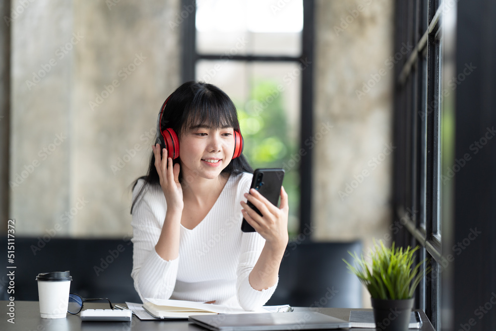 一名年轻的女学生坐在桌子旁，学习时使用电脑笔记本电脑。