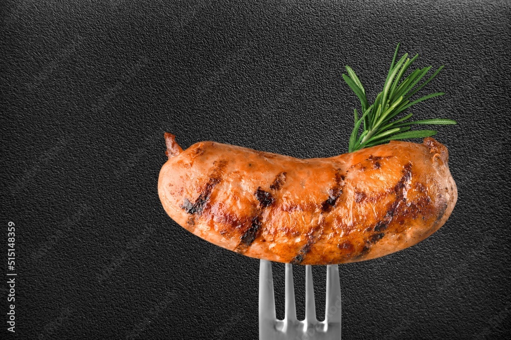 Tasty Grilled sausages with rosemary on a fork.