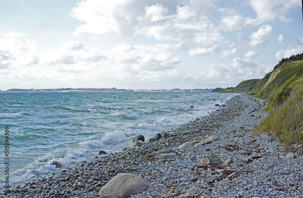 Coast of Kattegat - Helgenaes, Denmark. Ocean waves washing onto empty beach shore stones. Calm peac