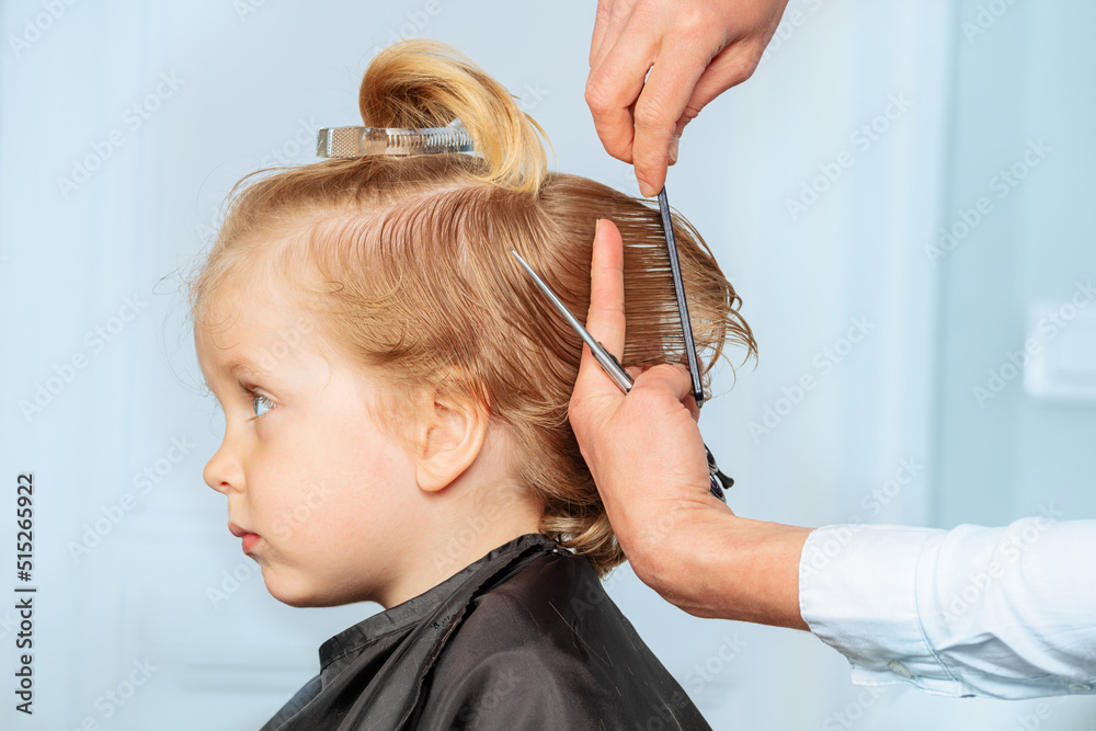 Profile of a 3 years old boy while hairstylist do haircut