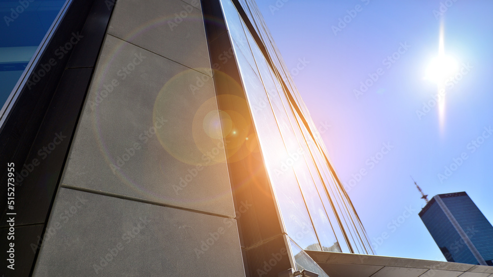 Bottom view of modern skyscraper in business district against blue sky. Looking up at business build